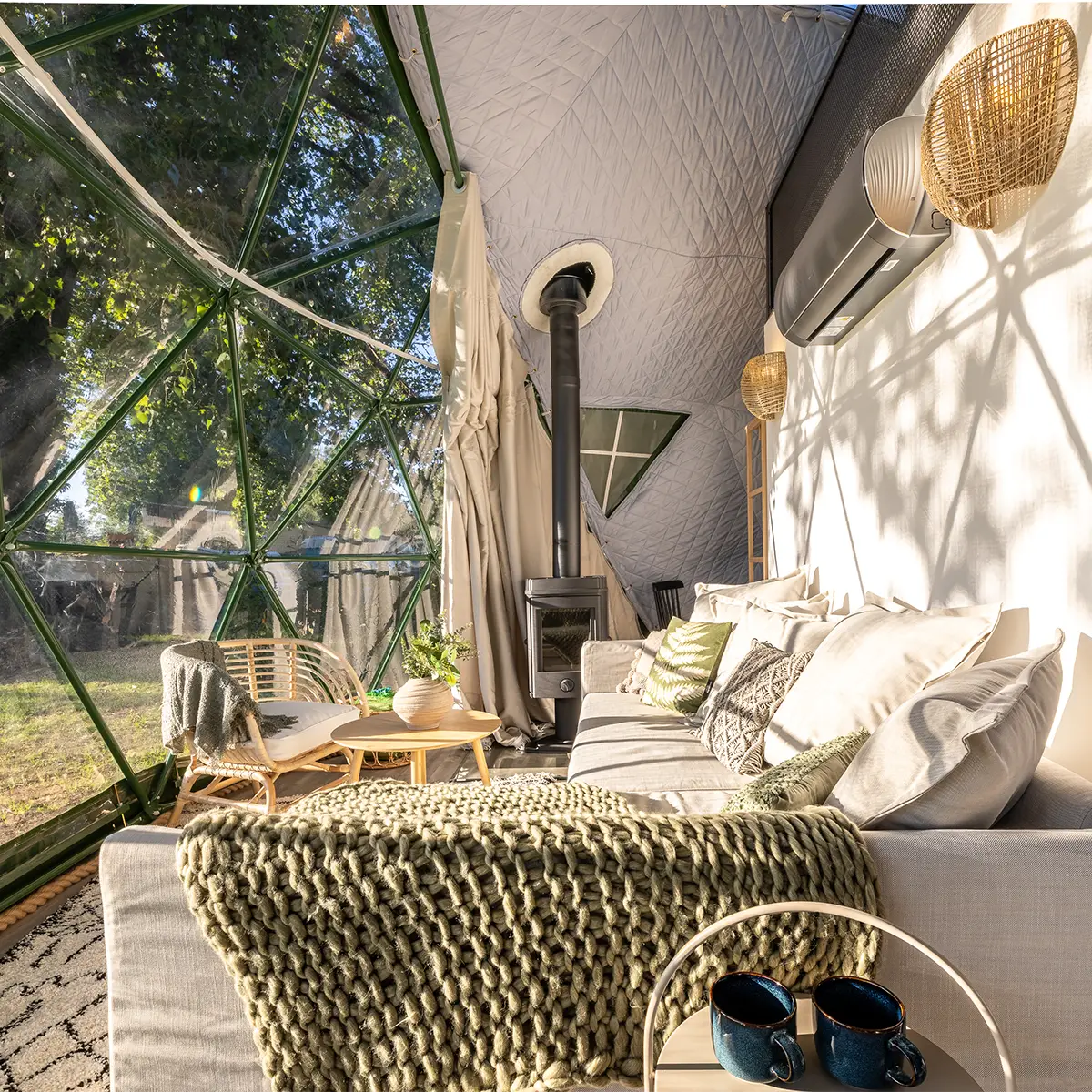 Morning inside the dome — knit blanket on the sofa, light through the panels