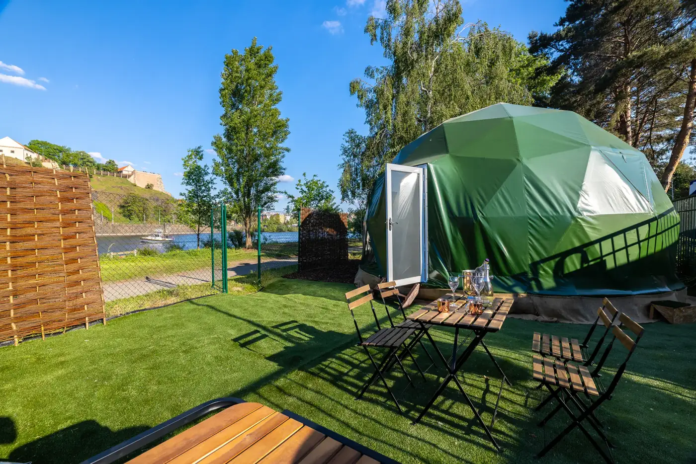Green geodesic dome on Císařská louca with the Vltava and Vyšehrad rock in the background